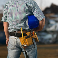 Person holding a helmet, overlooking an industrial work site.