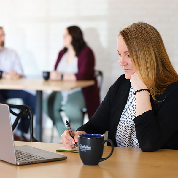 Underwriting associate taking notes while working on her laptop.